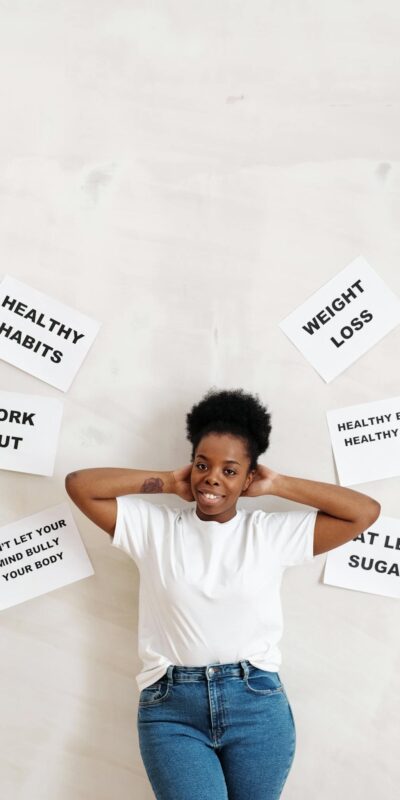 Woman standing against a wall with motivational slogans promoting health and fitness.