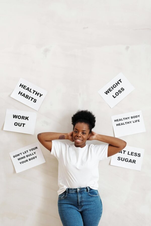 Woman standing against a wall with motivational slogans promoting health and fitness.